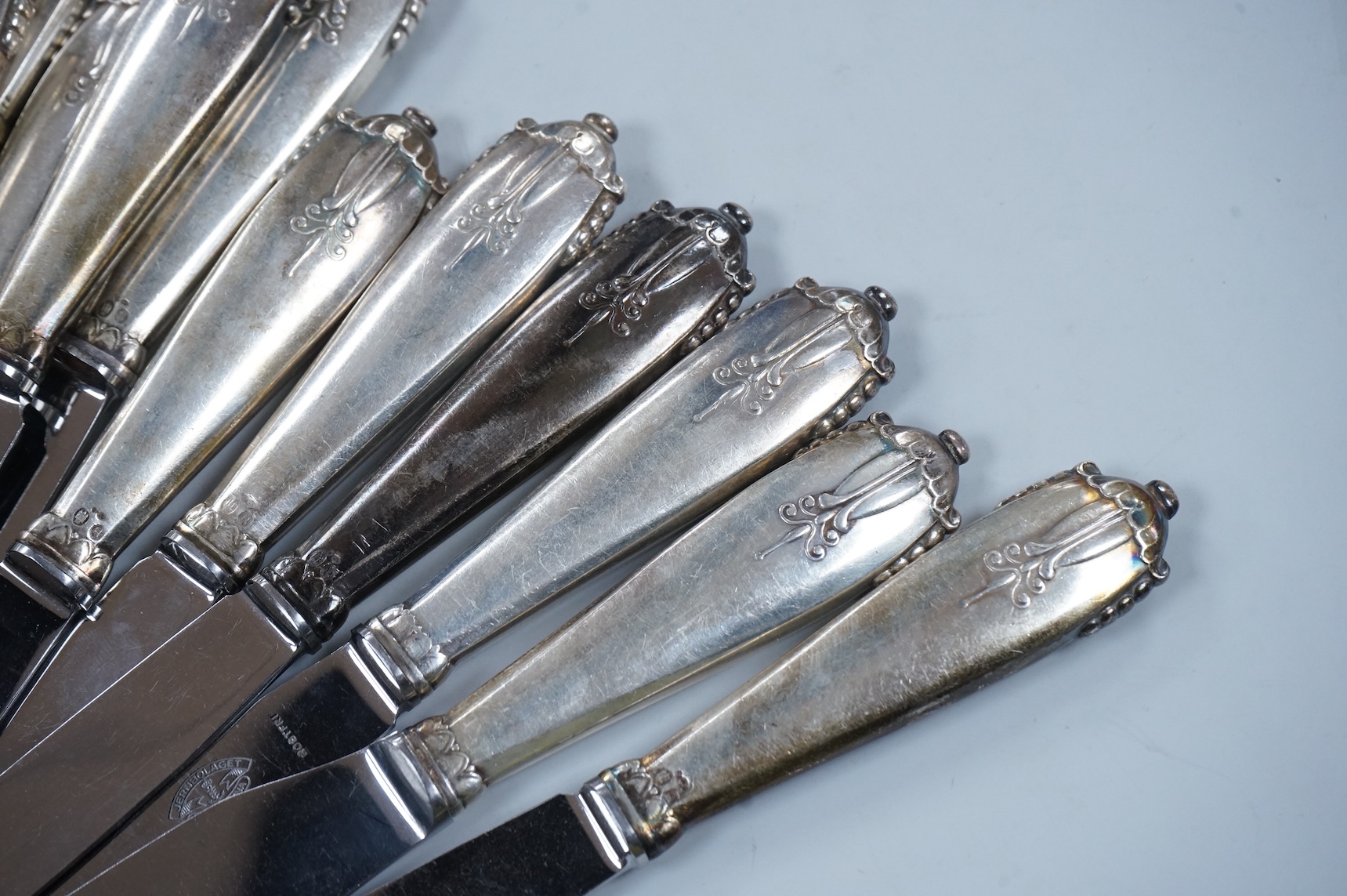 A George V loaded silver capstan-shaped inkwell, mm. W N Ltd, Birmingham 1931, 16.5cm diameter and twelve various Danish loaded silver handled knives with stainless steel blades